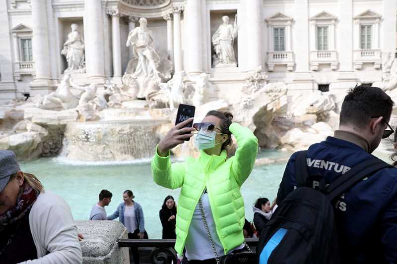 Woman in front of fountain taking selfie