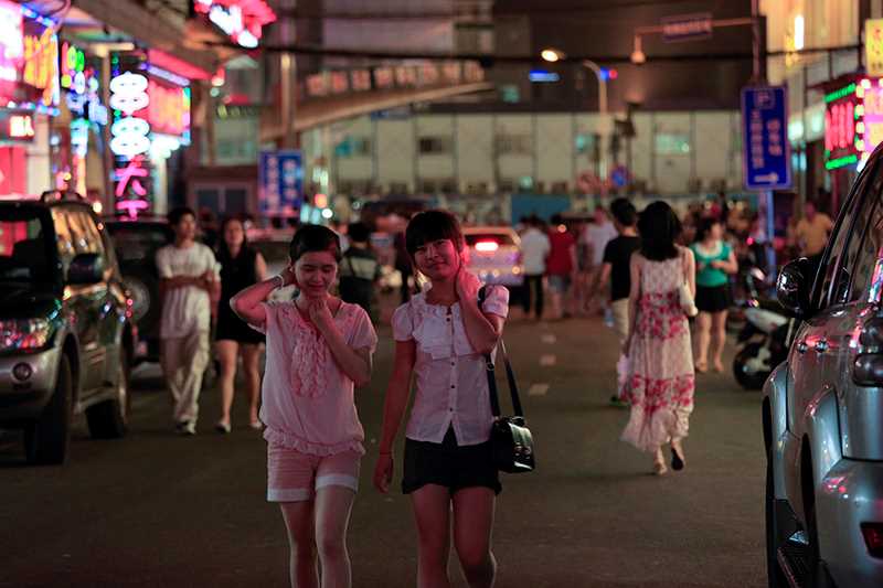 Two young Asian woman walking along a busy street.