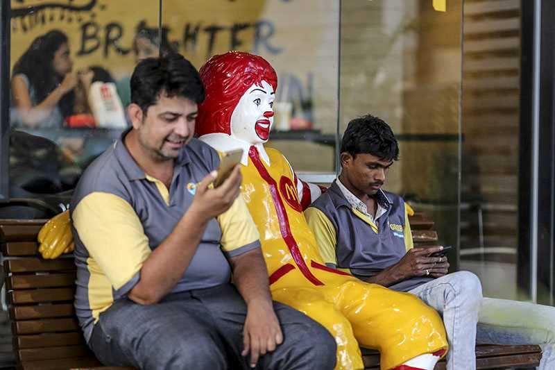 Two men on a bench with statue of Ronald McDonald