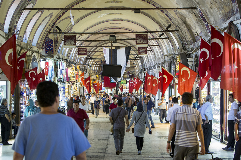 People walking in a market with Turkish flags on each side