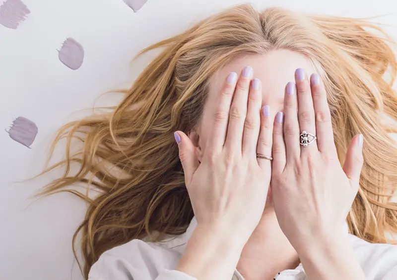 kvinne holder sine hender foran ansiktet